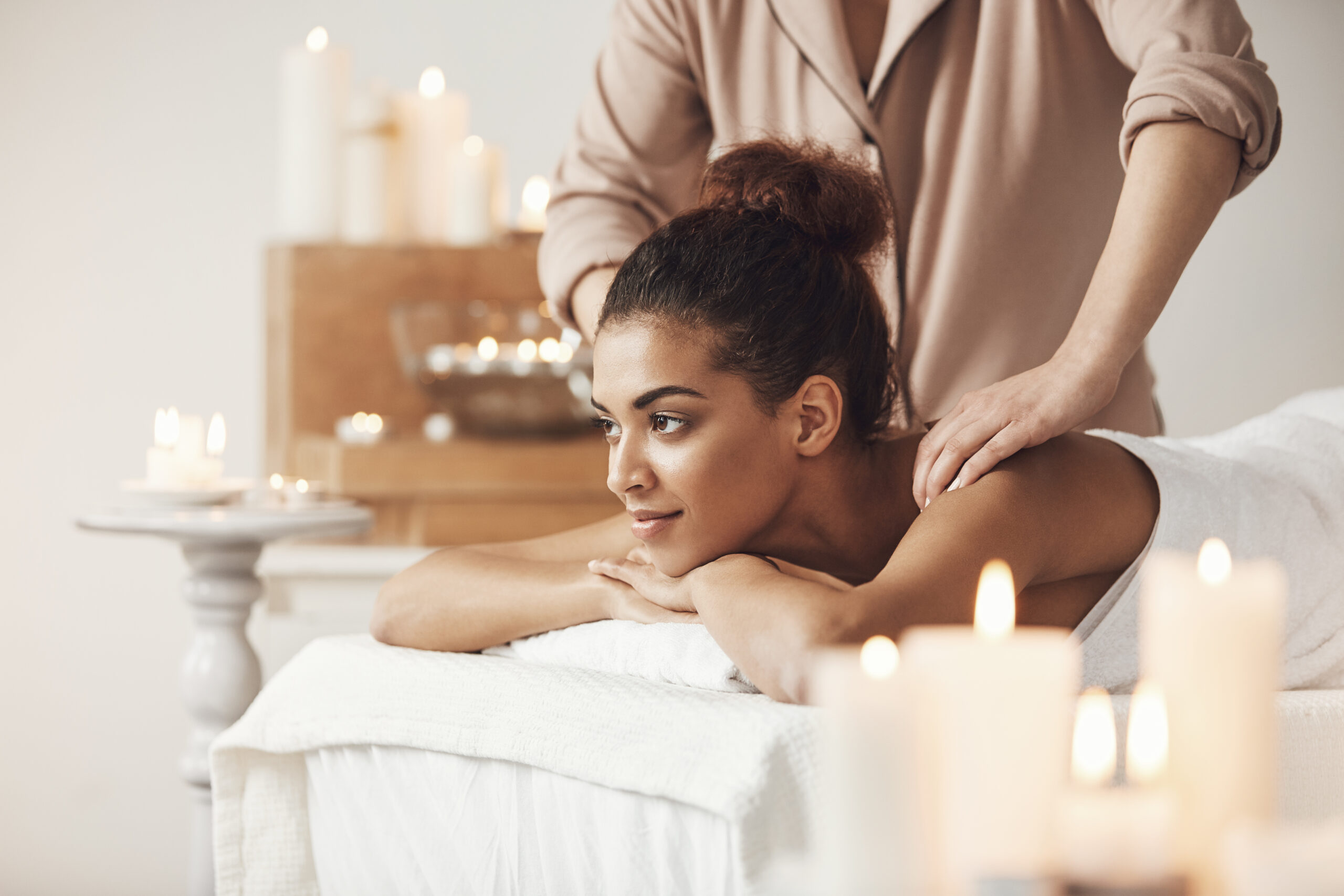 Young beautiful african girl smiling enjoying massage in spa resort.